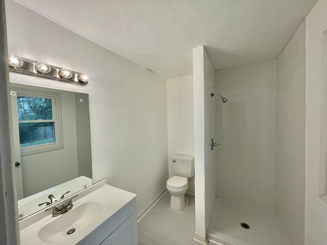 bathroom with a tile shower, vanity, a textured ceiling, and toilet