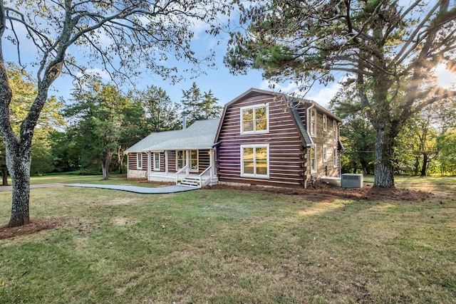 view of front facade featuring central AC unit, covered porch, and a front yard