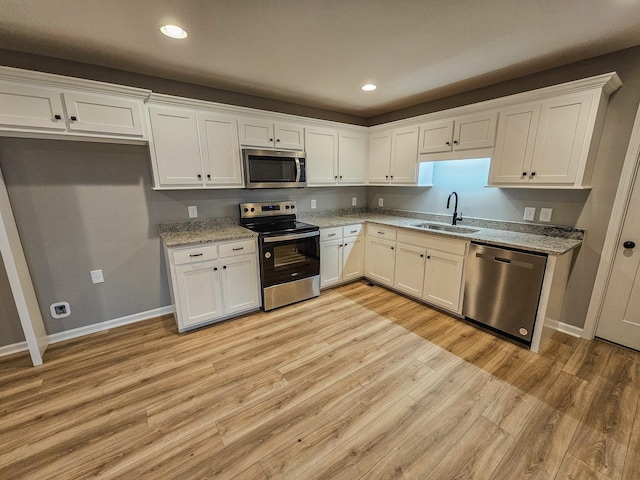 kitchen with stainless steel appliances, sink, white cabinets, and light stone counters