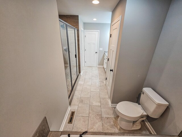 bathroom featuring vanity, toilet, and a shower with door