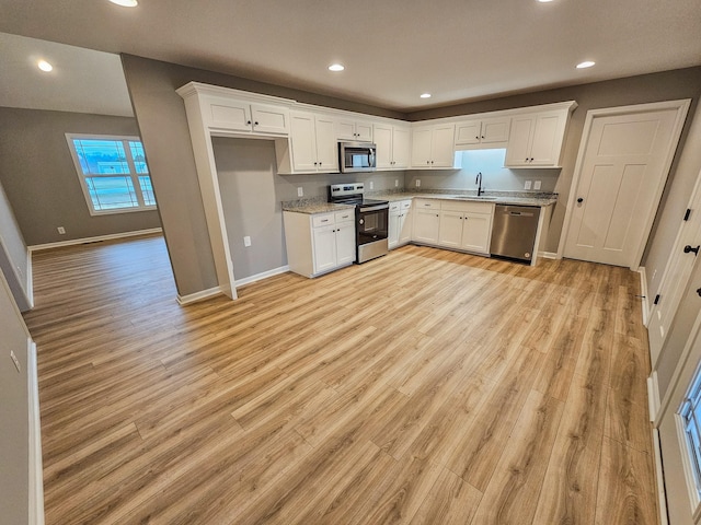 kitchen featuring stainless steel appliances, sink, white cabinets, and light wood-type flooring