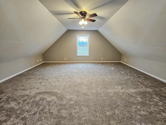 additional living space featuring vaulted ceiling and dark colored carpet