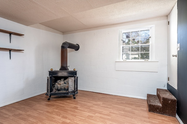 room details with hardwood / wood-style floors, a wood stove, and a textured ceiling