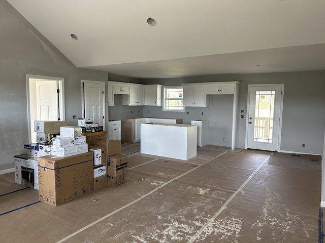 kitchen with vaulted ceiling, a kitchen island, and white cabinets