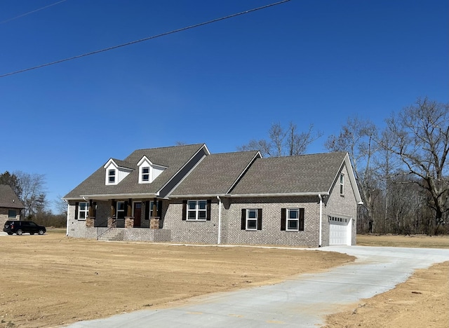 view of front of home with a garage, covered porch, driveway, and brick siding