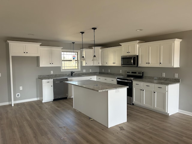 kitchen featuring stainless steel appliances, hanging light fixtures, a center island, and white cabinets