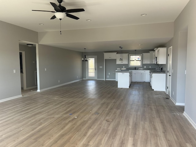 unfurnished living room with ceiling fan, wood-type flooring, and sink