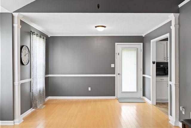 foyer featuring ornate columns, light hardwood / wood-style flooring, and ornamental molding