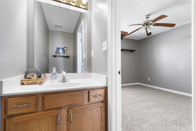 bathroom with ceiling fan, vanity, and a textured ceiling