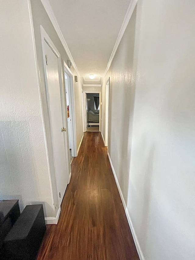 hallway featuring baseboards, crown molding, and wood finished floors