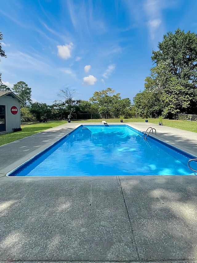 outdoor pool with a patio and a lawn