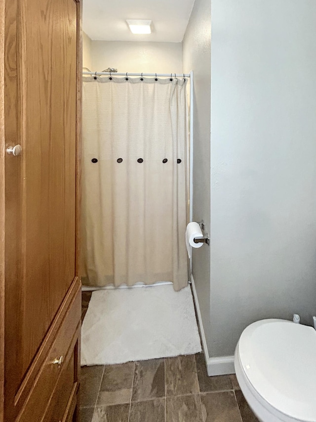 full bathroom with baseboards, toilet, and a shower with shower curtain