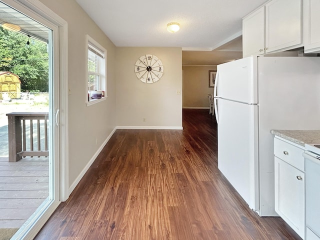 kitchen with baseboards, dark wood finished floors, freestanding refrigerator, and white cabinetry