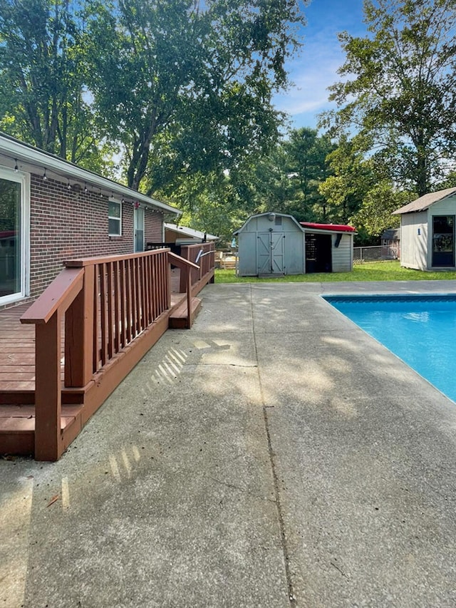 view of swimming pool featuring a storage shed, a deck, an outbuilding, and a fenced in pool