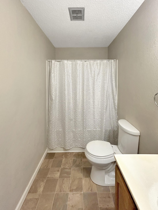 bathroom with a textured ceiling, toilet, vanity, visible vents, and baseboards