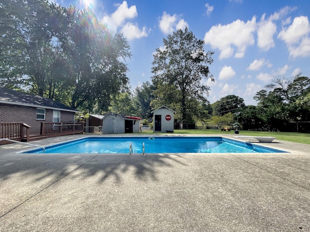 outdoor pool featuring a storage shed, a wooden deck, a diving board, and an outdoor structure