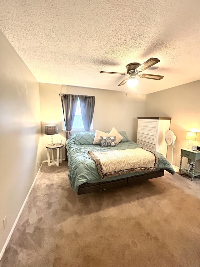 carpeted bedroom with a textured ceiling, a ceiling fan, and baseboards