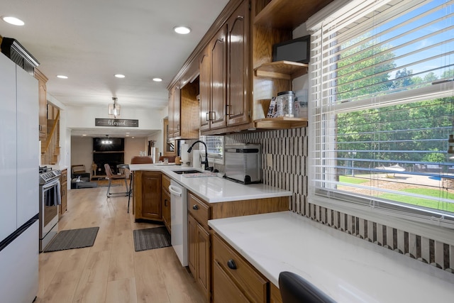 kitchen with decorative backsplash, appliances with stainless steel finishes, light hardwood / wood-style flooring, and sink