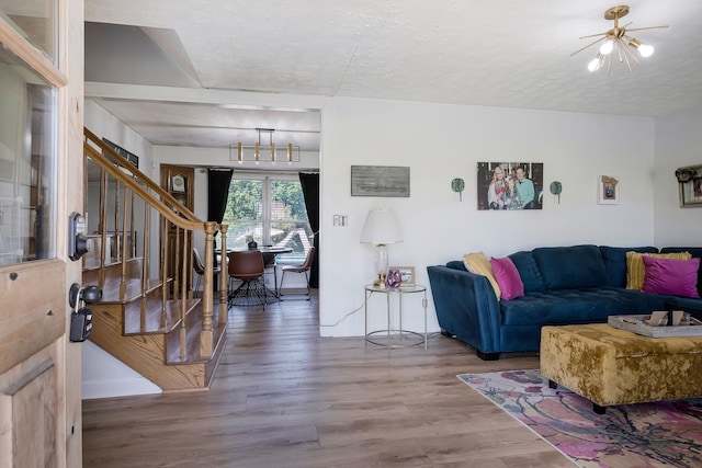 living room featuring a notable chandelier, wood-type flooring, and a textured ceiling