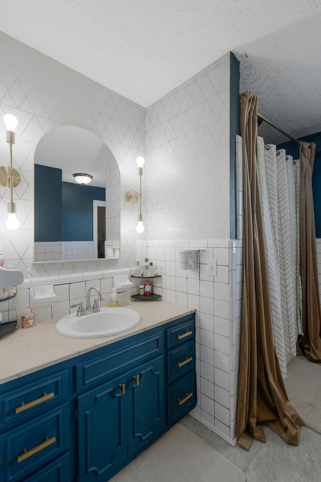 bathroom featuring a textured ceiling, tile patterned floors, vanity, and tile walls