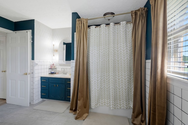 bathroom featuring vanity, a textured ceiling, tile patterned floors, and tile walls