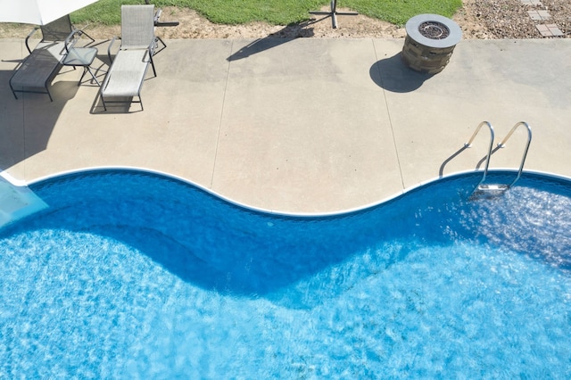 view of swimming pool with an outdoor fire pit and a patio