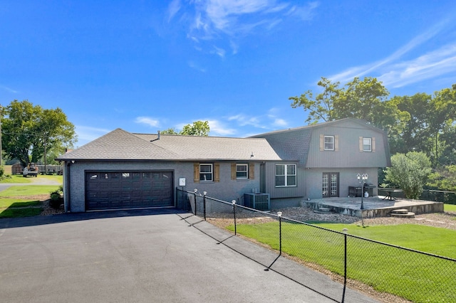 view of front of home featuring a garage, a front lawn, and central air condition unit