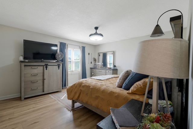 bedroom with light hardwood / wood-style floors and a textured ceiling