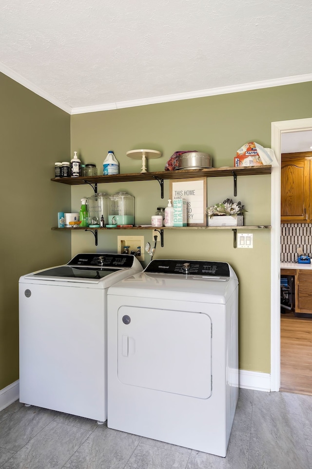 washroom with light tile patterned floors, a textured ceiling, ornamental molding, and washing machine and clothes dryer