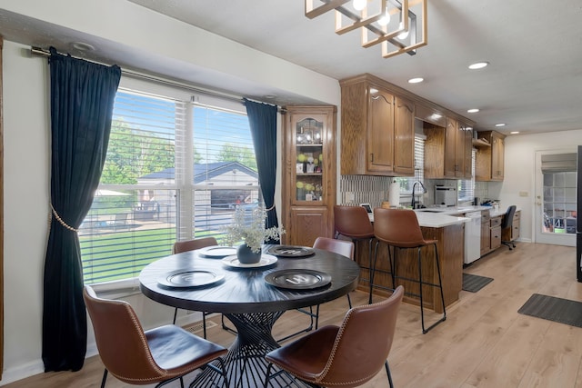 dining room featuring light wood-type flooring, an inviting chandelier, and sink