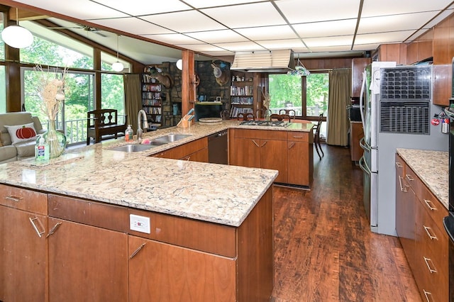 kitchen featuring dishwasher, lofted ceiling, dark wood-type flooring, sink, and wooden walls