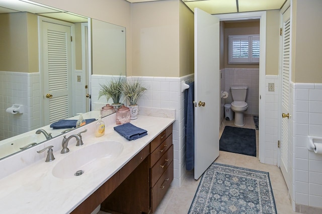 bathroom featuring tile patterned flooring, vanity, tile walls, and toilet