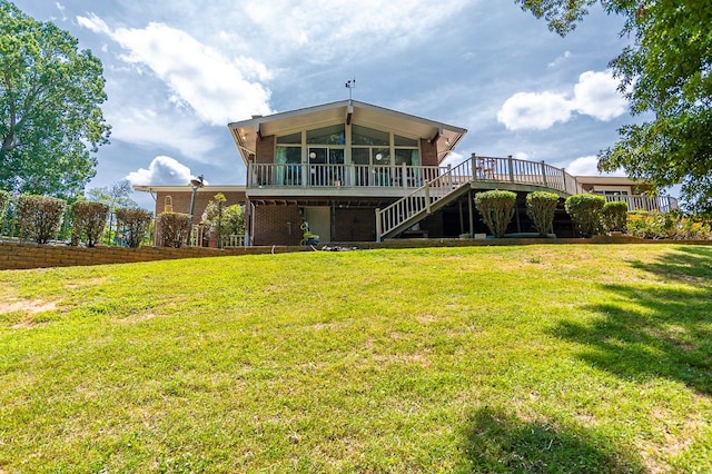 rear view of house featuring a lawn, a sunroom, and a deck