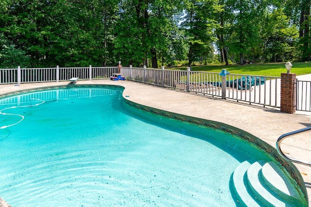 view of swimming pool featuring a diving board and a patio area