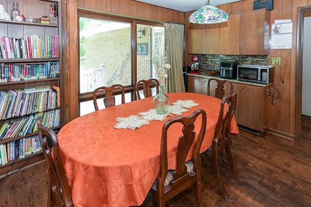 dining room featuring wood walls and dark hardwood / wood-style flooring