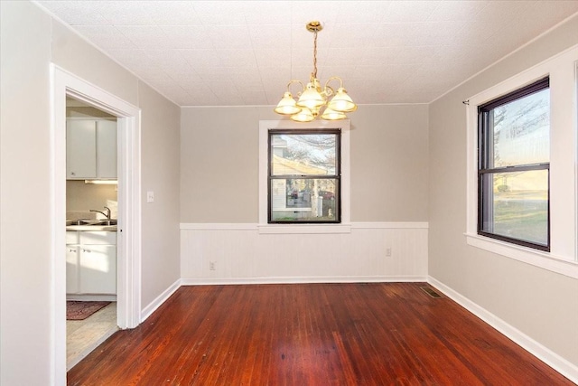 spare room with dark hardwood / wood-style floors, sink, and a chandelier