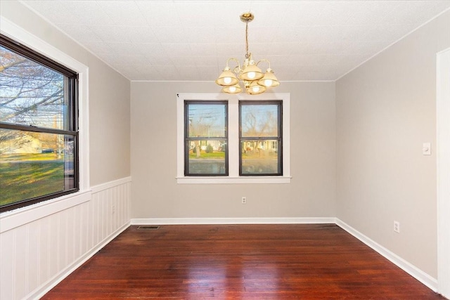 empty room with a notable chandelier and hardwood / wood-style flooring