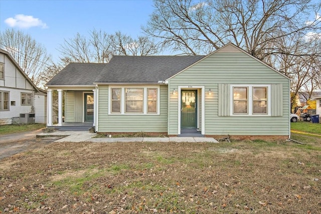 view of front of home with cooling unit, a front lawn, and covered porch