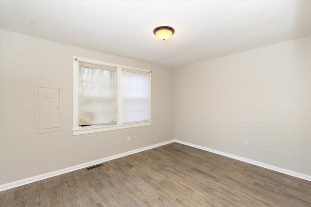 empty room featuring electric panel and hardwood / wood-style flooring