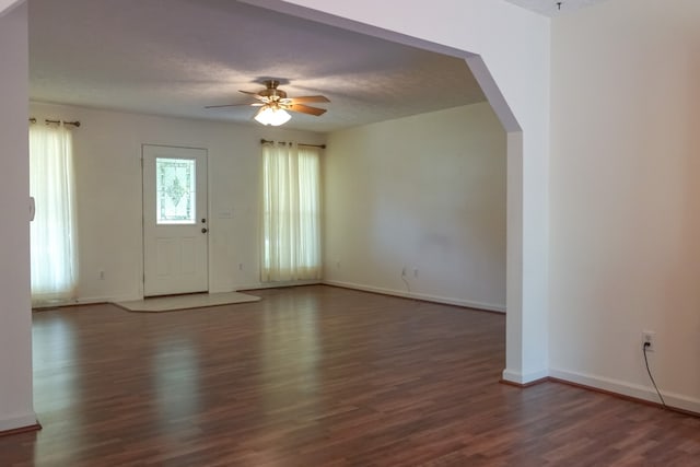 empty room featuring a textured ceiling, ceiling fan, and dark wood-type flooring