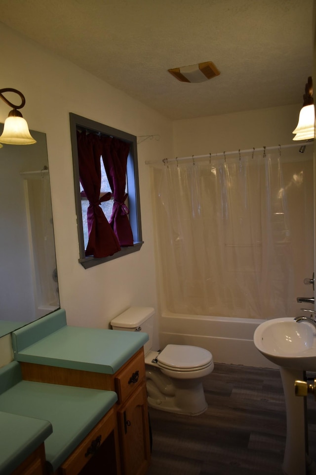 bathroom with hardwood / wood-style floors, toilet, and shower / bath combo with shower curtain