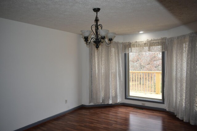 unfurnished dining area with dark hardwood / wood-style flooring, a textured ceiling, and a chandelier