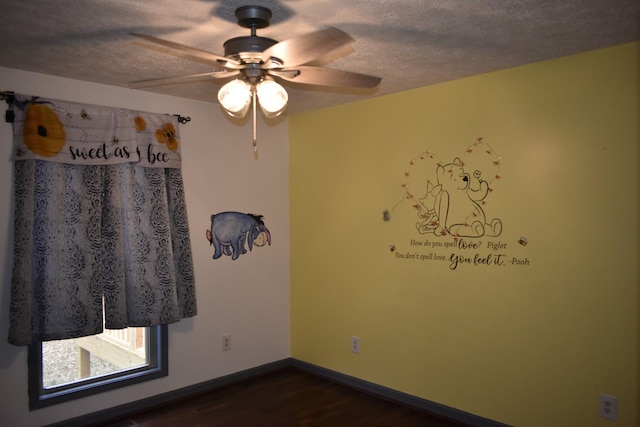 empty room with dark hardwood / wood-style floors, ceiling fan, and a textured ceiling