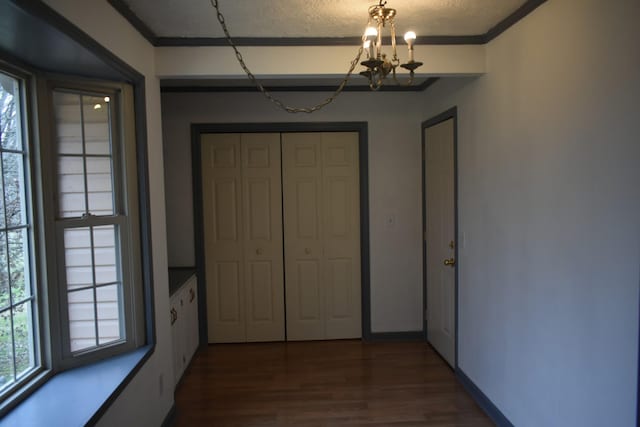 interior space featuring dark hardwood / wood-style flooring, ornamental molding, a textured ceiling, and an inviting chandelier