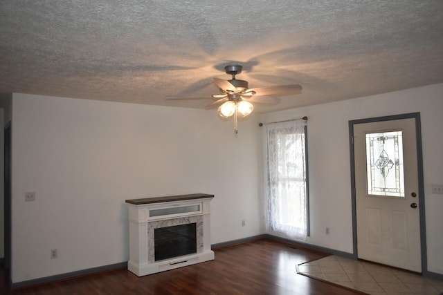 unfurnished living room with a fireplace, ceiling fan, and dark hardwood / wood-style flooring