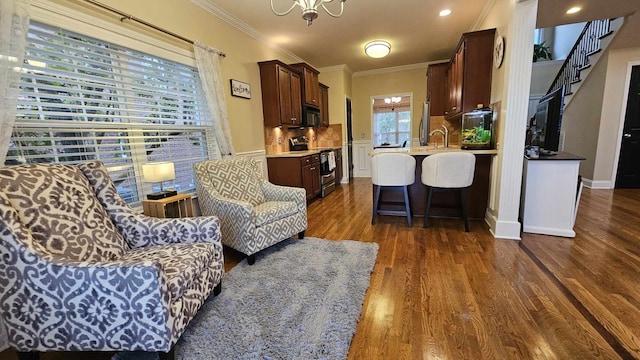 living room featuring dark hardwood / wood-style floors, an inviting chandelier, crown molding, and sink