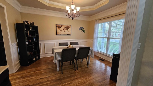 dining area featuring a raised ceiling, dark hardwood / wood-style flooring, ornamental molding, and an inviting chandelier