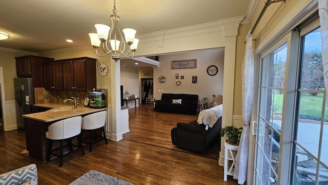 kitchen with dark wood-type flooring, a kitchen breakfast bar, refrigerator, sink, and hanging light fixtures