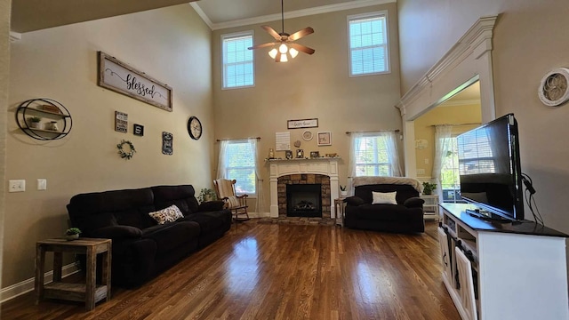 living room featuring a fireplace, crown molding, a towering ceiling, and dark wood-type flooring