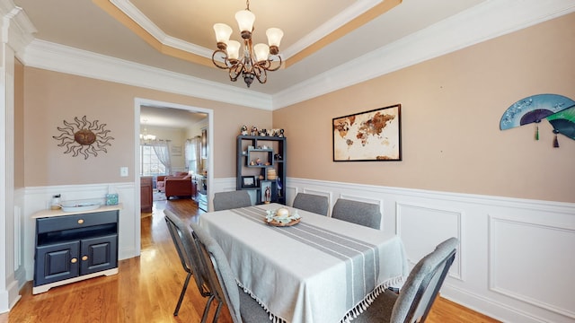 dining room with ornamental molding, light hardwood / wood-style flooring, and a chandelier